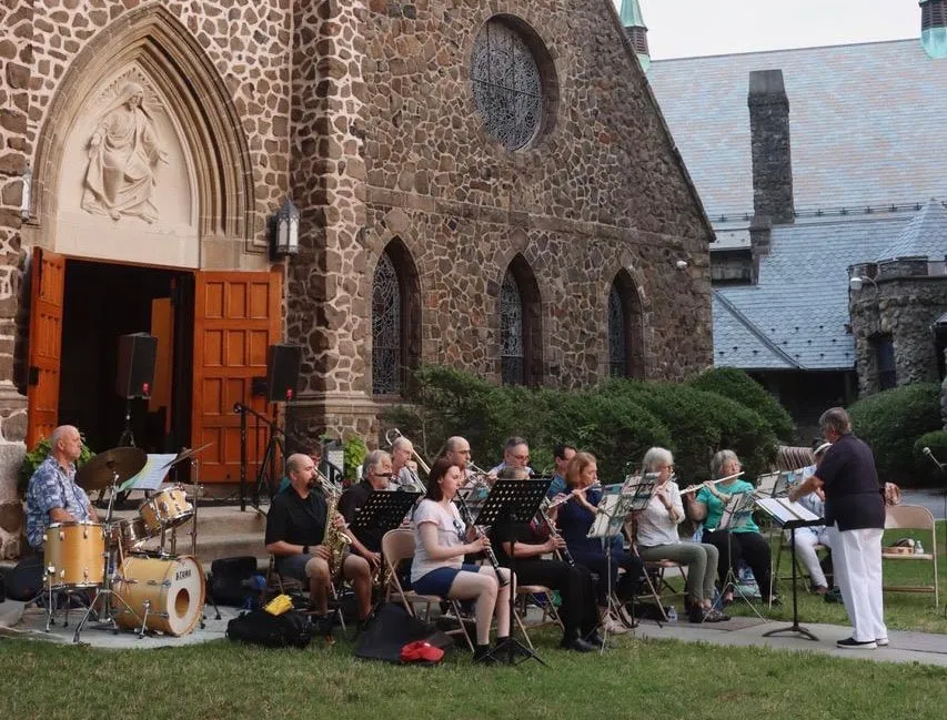 A community band plays outside the open front doors of St. James, beneath the carved tympanum